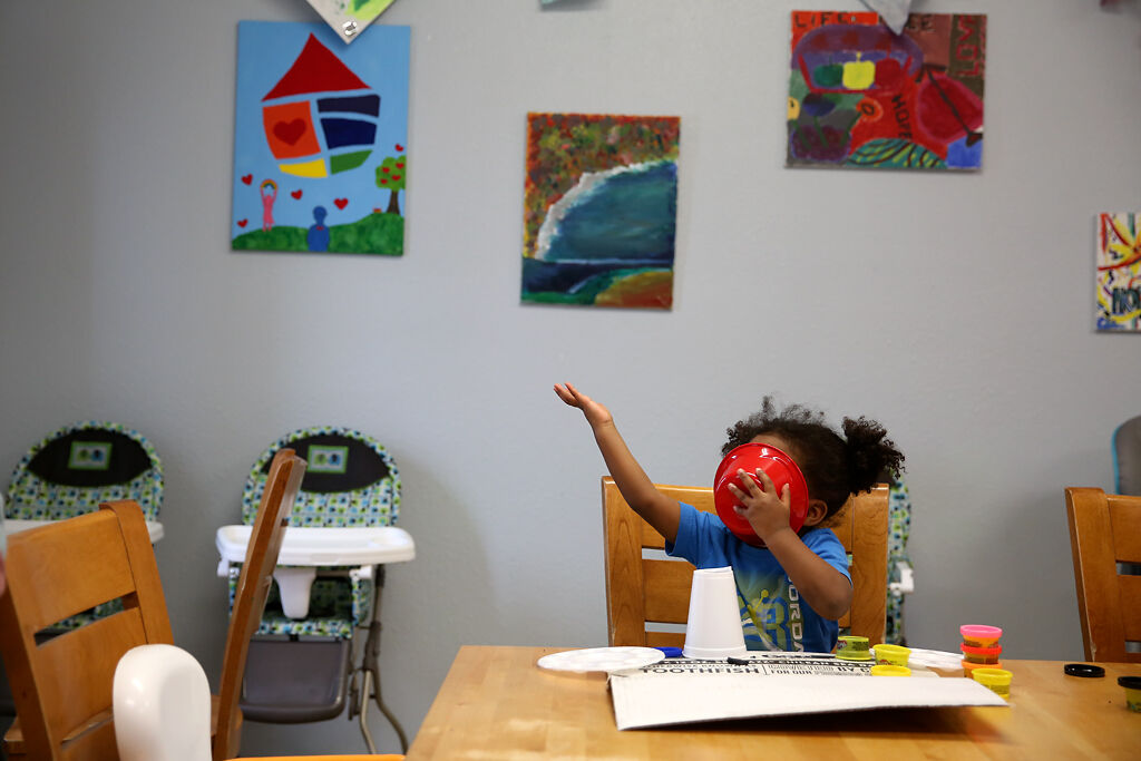 A child staying at Rainbow House shoves their face into a bowl